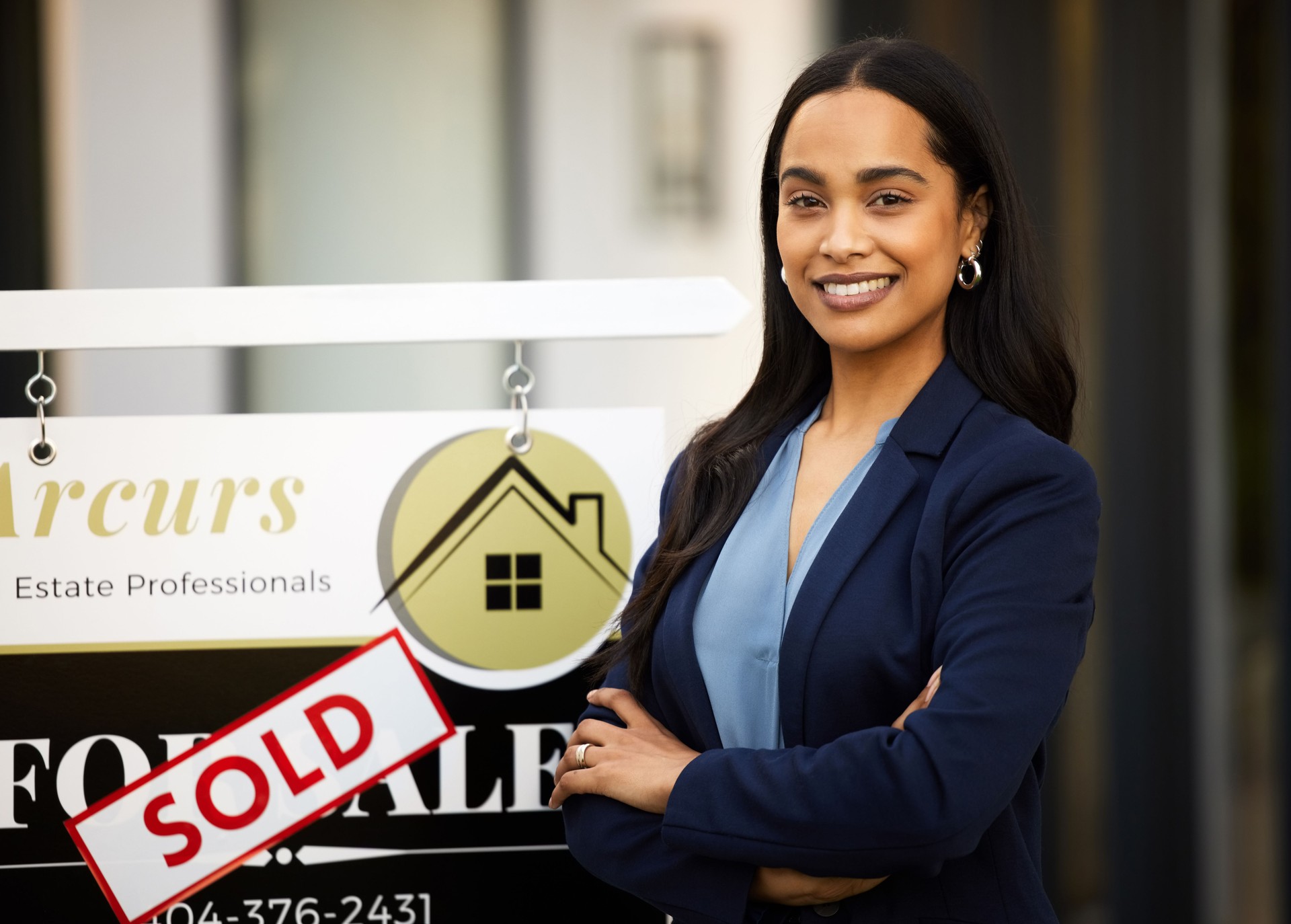 Cropped portrait of an attractive young real estate agent standing with her arms crossed next to a sold sign outside of a recently sold home